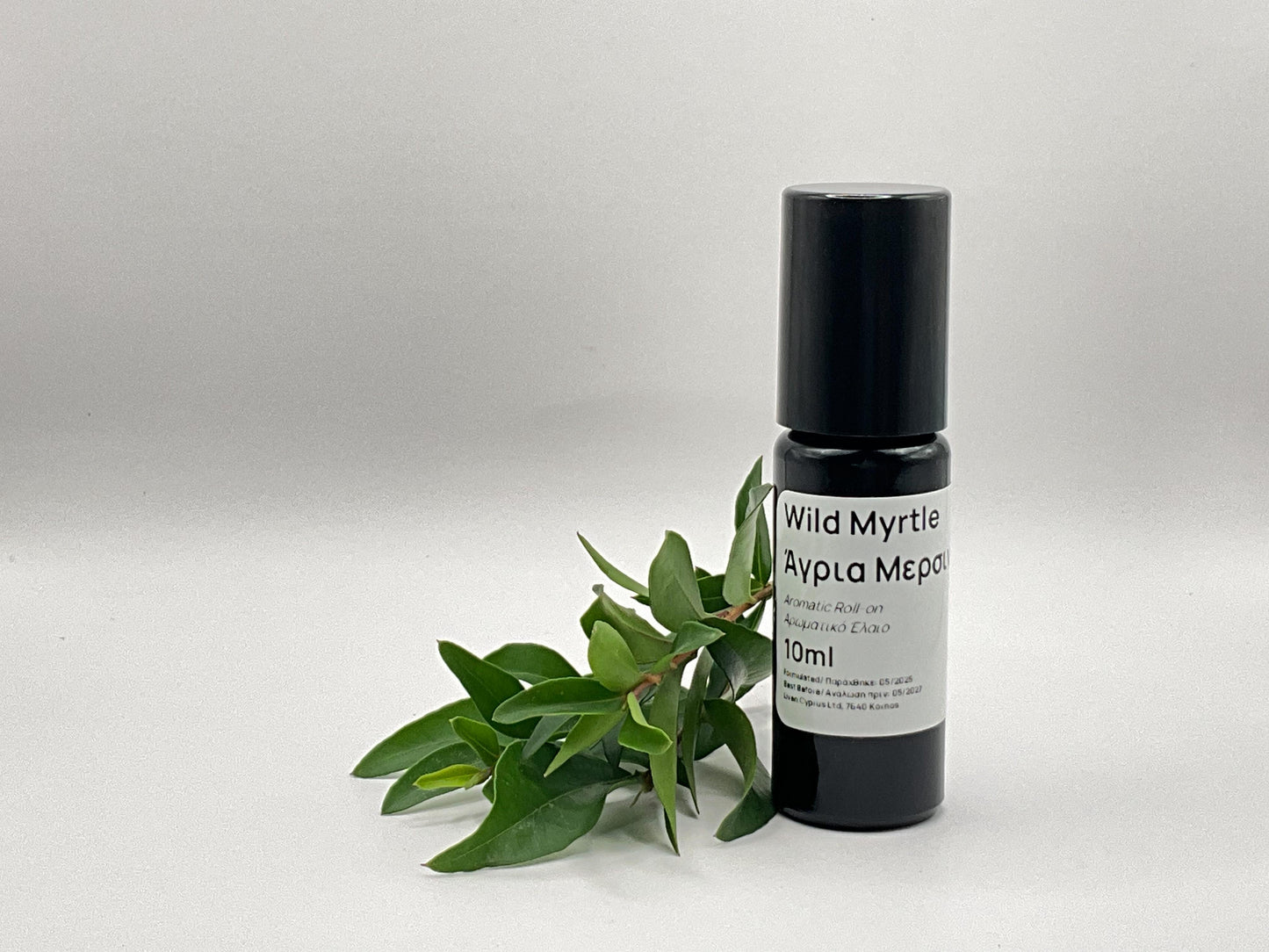 Small black bottle labeled 'Wild Myrtle roll on with a green leaf branch on a light gray background