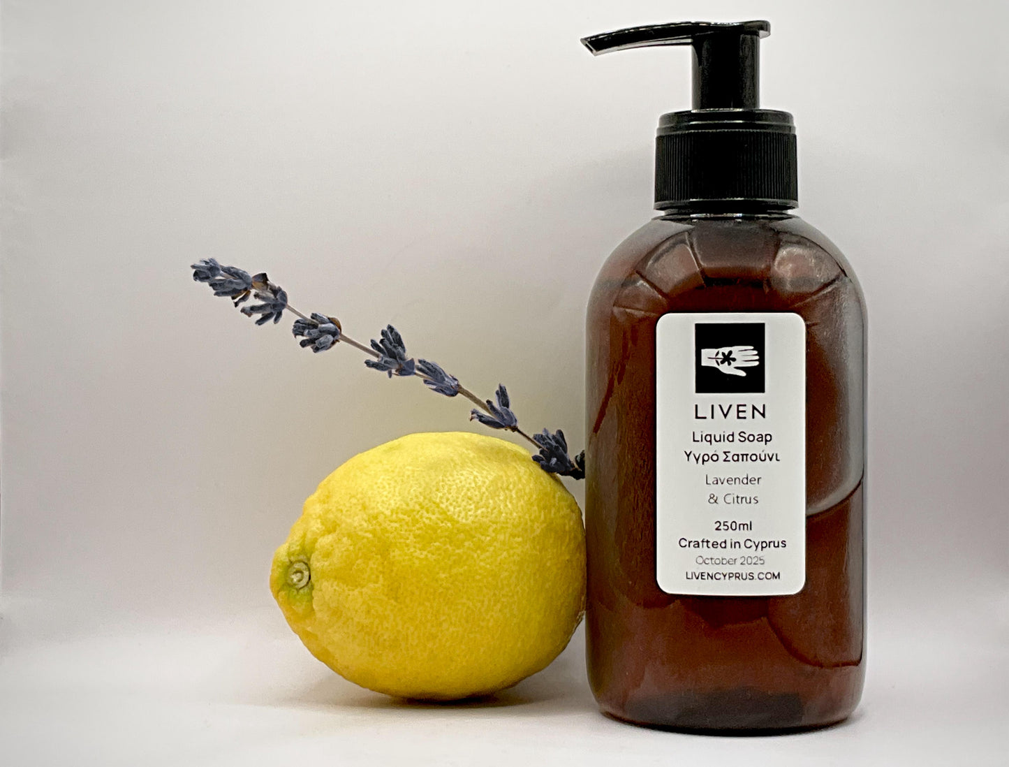 Brown bottle of LIVEN liquid soap with a lemon and lavender sprig on a light background