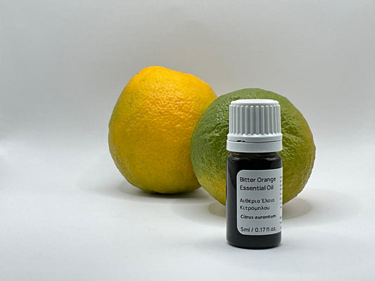 Bottle of bitter orange essential oil with two oranges on a white background