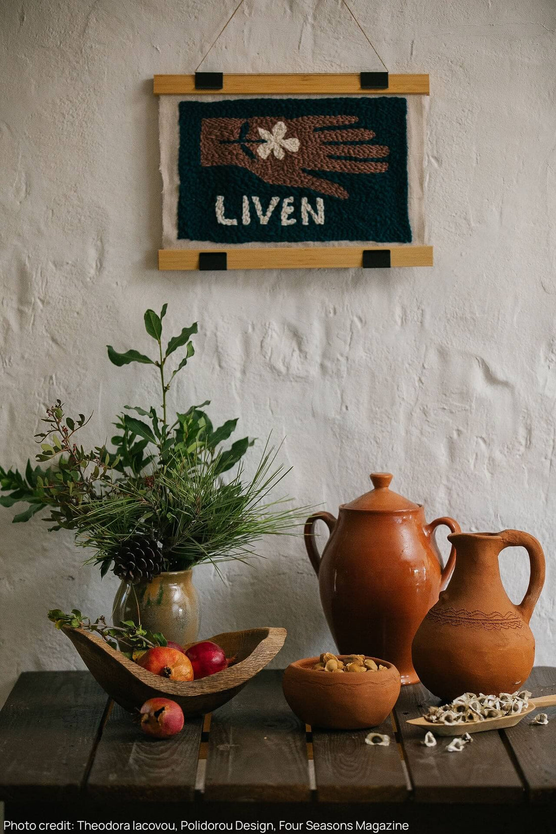 Table with terracotta vessels filled with seeds and botanicals, above there's a liven embroidered logo
