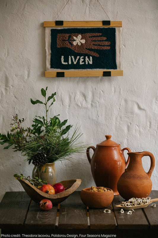 Table with terracotta vessels filled with seeds and botanicals, above there's a liven embroidered logo