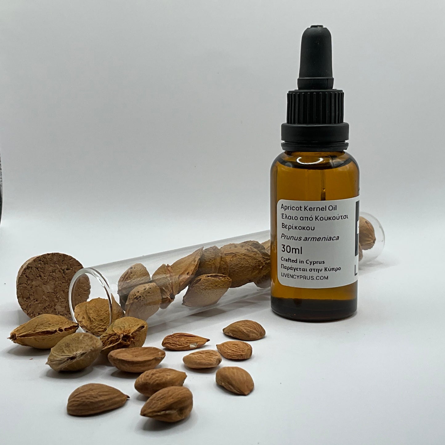 Bottle of apricot kernel oil with almonds on a white background