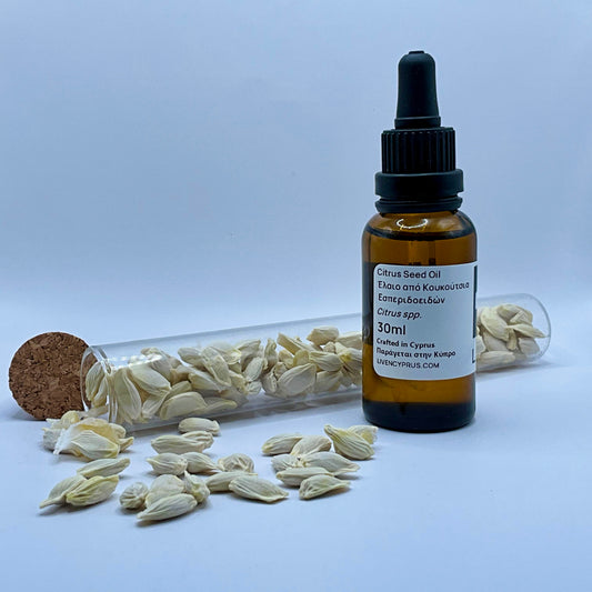 Amber glass bottle with dropper labeled 'Citrus Seed Oil' on a light gray background with scattered seeds.
