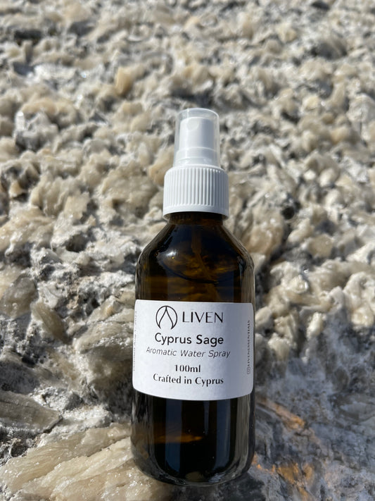 A brown glass spray bottle labeled 'Cyprus Sage' placed on a textured stone surface.