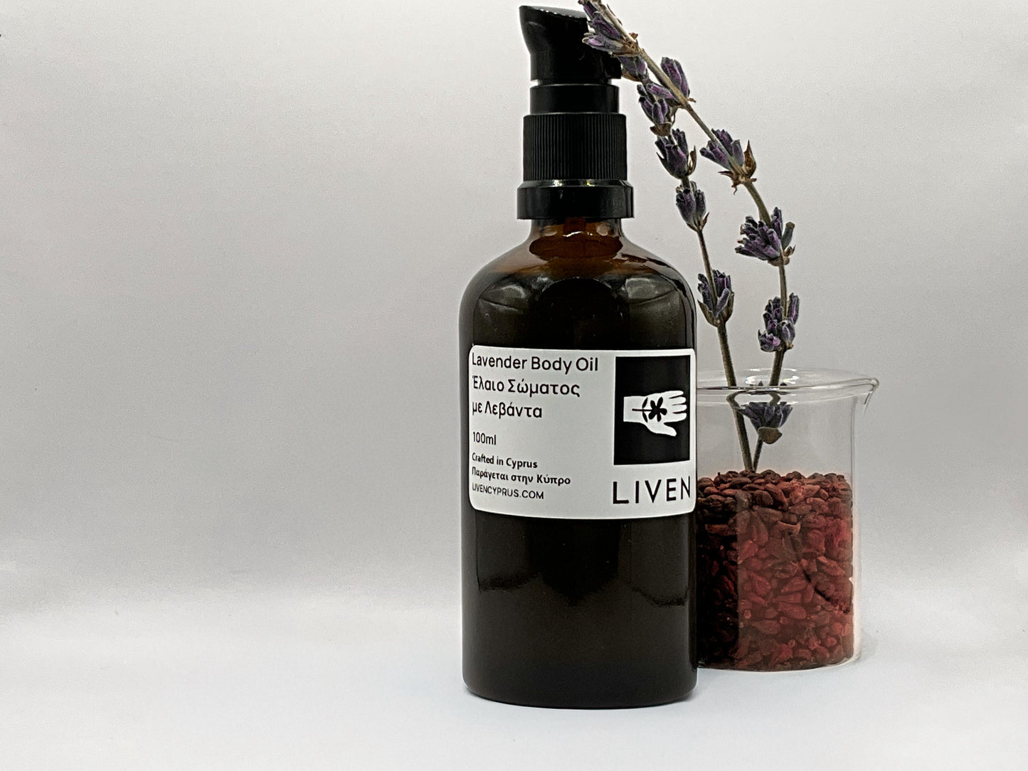 Lavender body oil bottle with a label, lavender flowers, and red berries on a white background