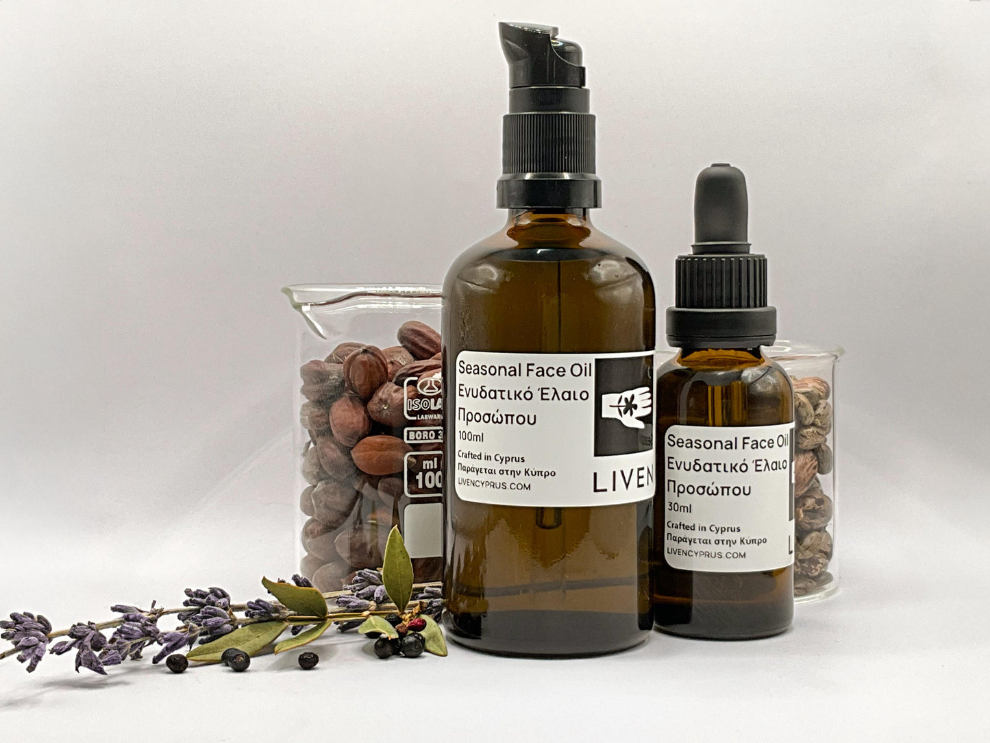 Two bottles of 'LIVE!' brand face oils with a container of nuts and lavender and other Cyprus botanicals