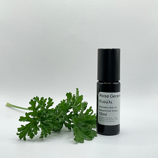Black rollerball bottle with rose geranium leaves on a white background