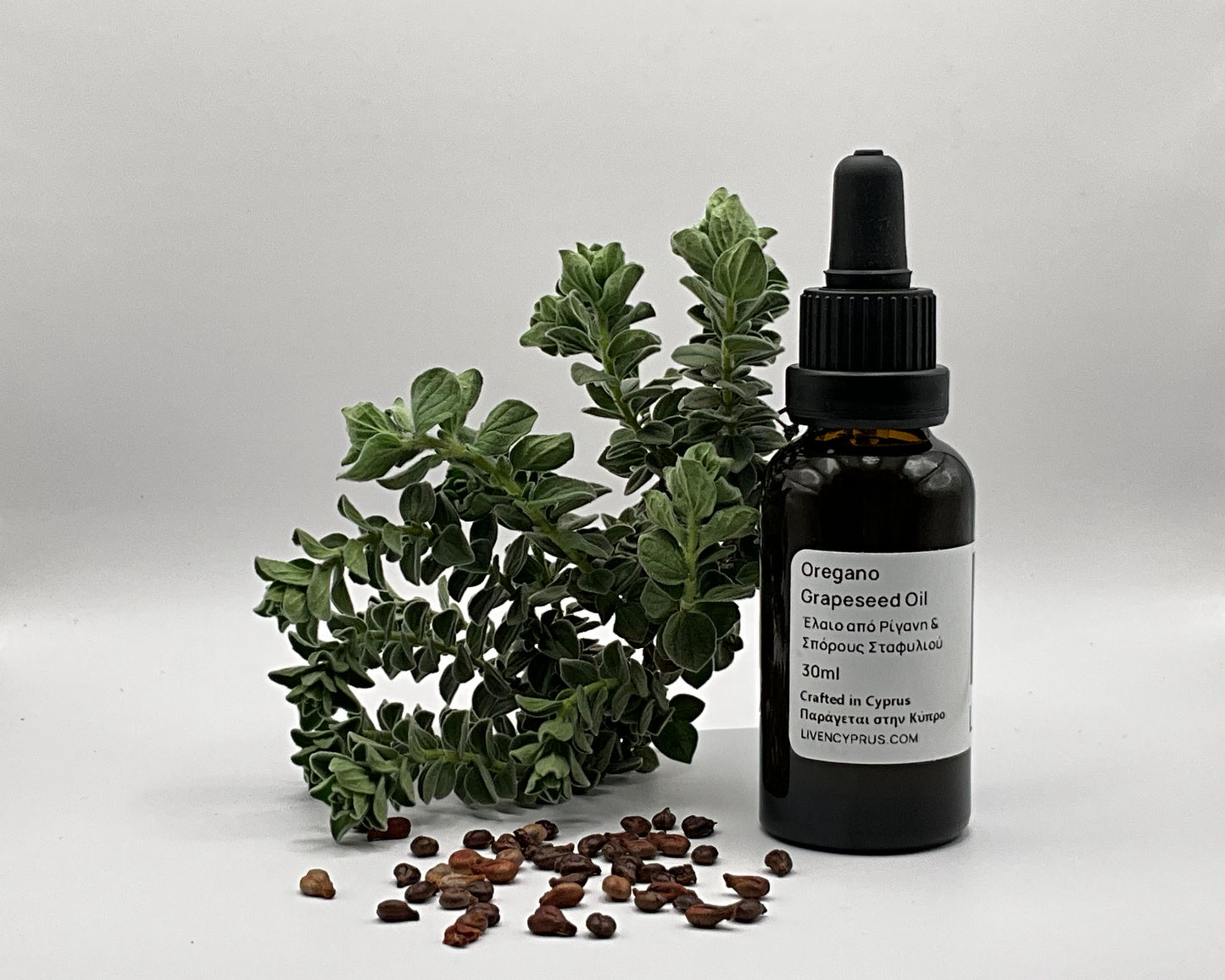 Bottle of oregano oil with fresh oregano leaves and grapeseeds on a white background