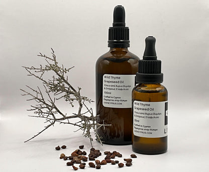 Two bottles of Wild Thyme Grapeseed Oil with a branch and seeds on a light background