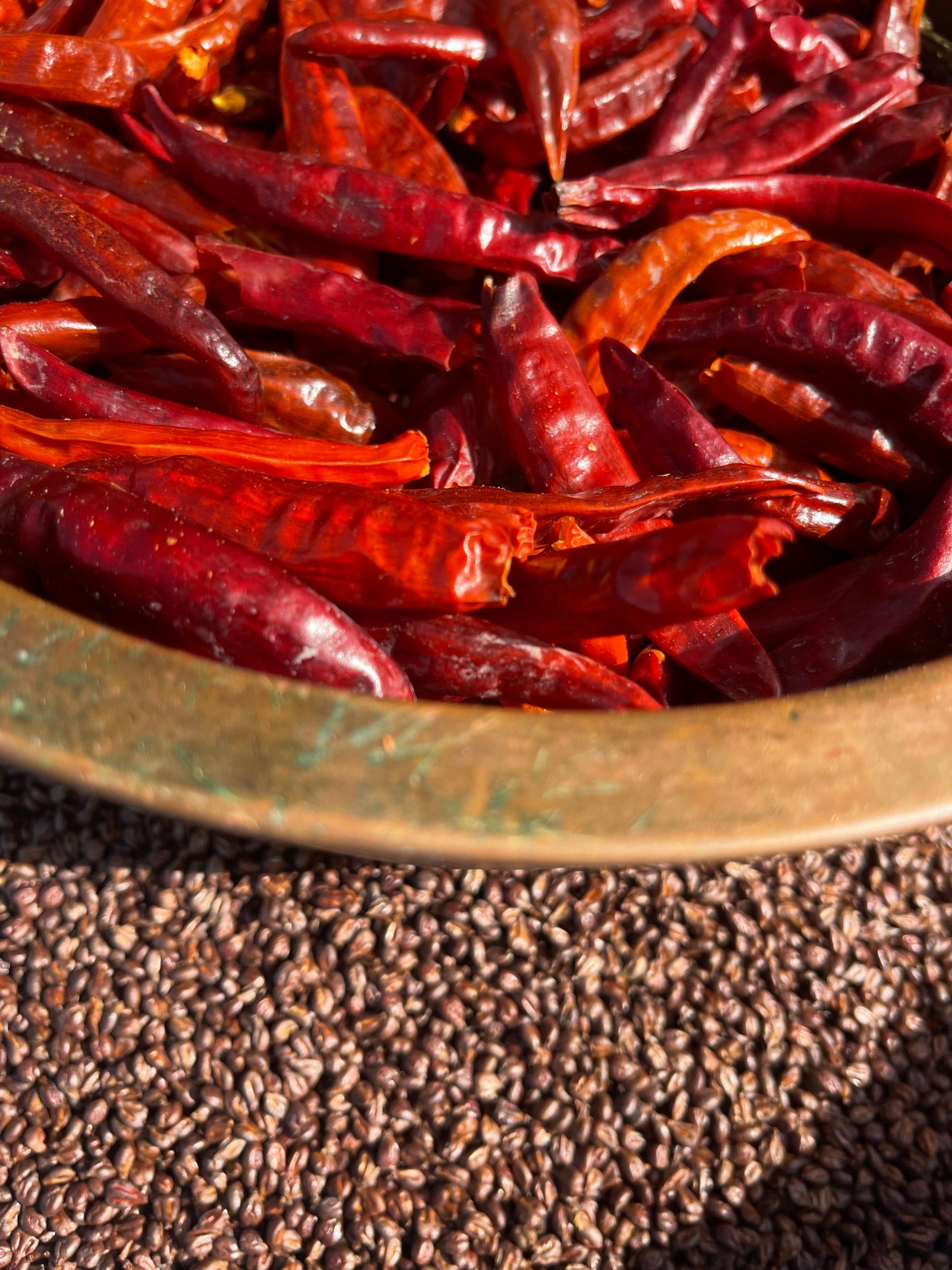 Dried red chili peppers in a brass bowl and grapeseed
