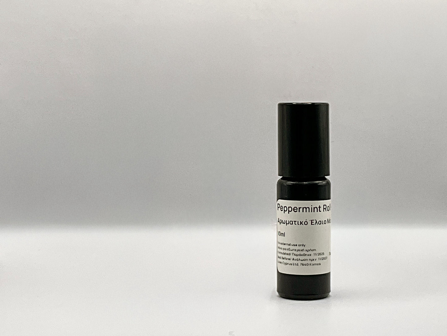 Peppermint roll-on bottle with black cap and white label on a gray background