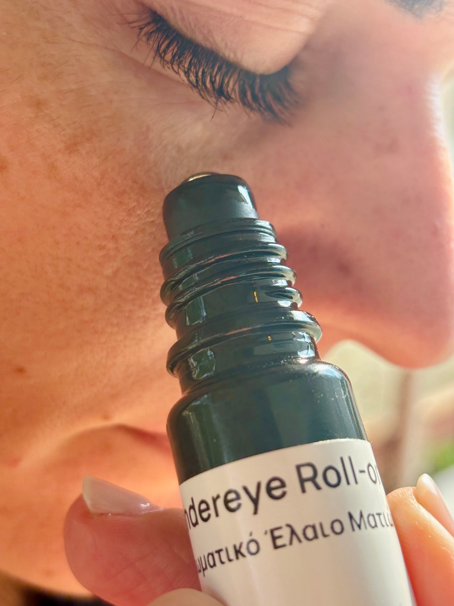 Close-up of a person holding a 'undereye Roll-on' bottle near their eye.