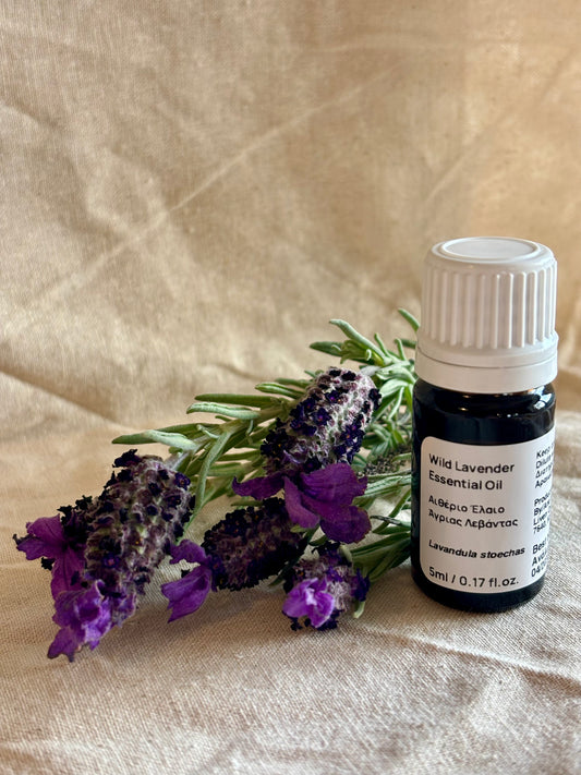 A small bottle of Wild Cyprus or Spanish Lavender Essential Oil next to a sprig of lavender flowers on a light background.