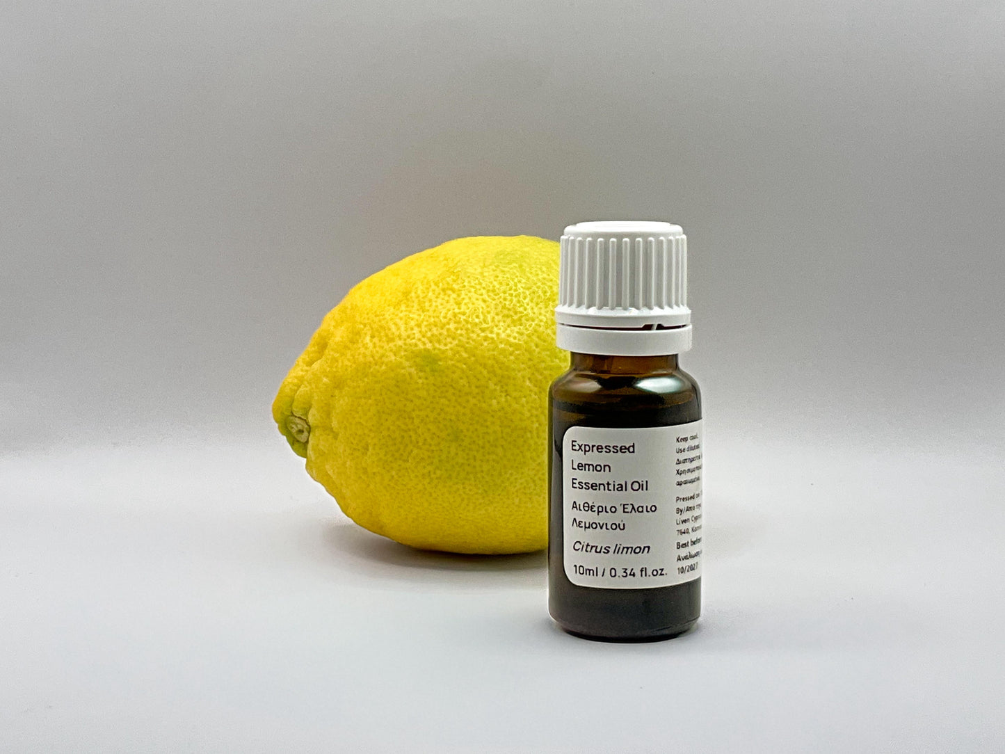 Bottle of lemon essential oil next to a Cyprus lemon 